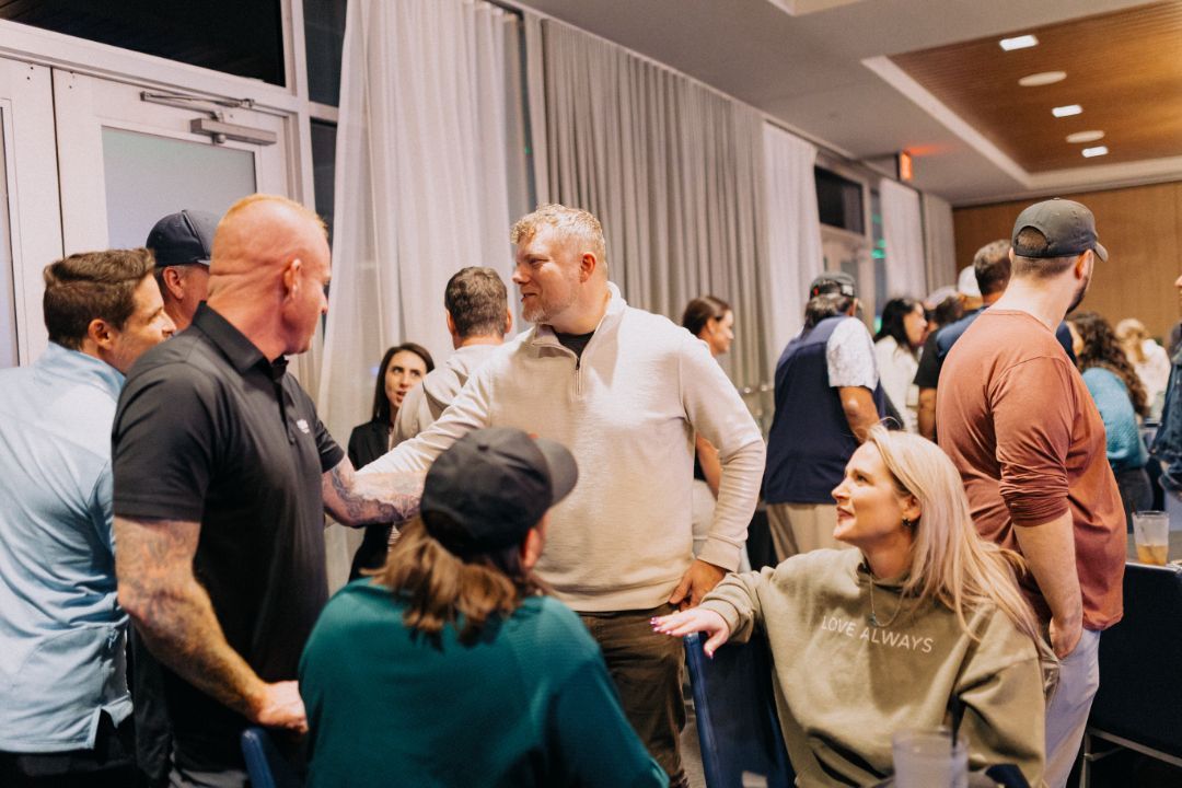 A group of people are standing in a room talking to each other.