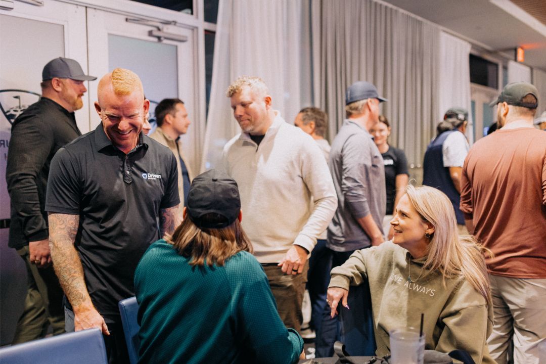 A group of people are standing around a table talking to each other.