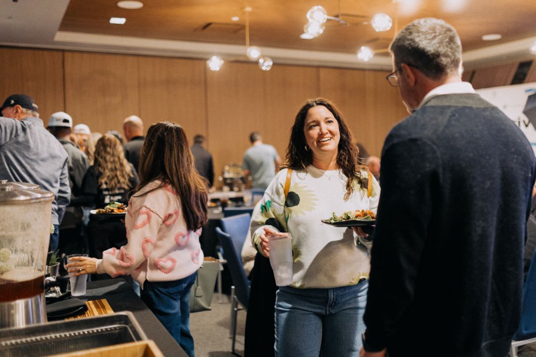 A group of people are standing in a room talking to each other.