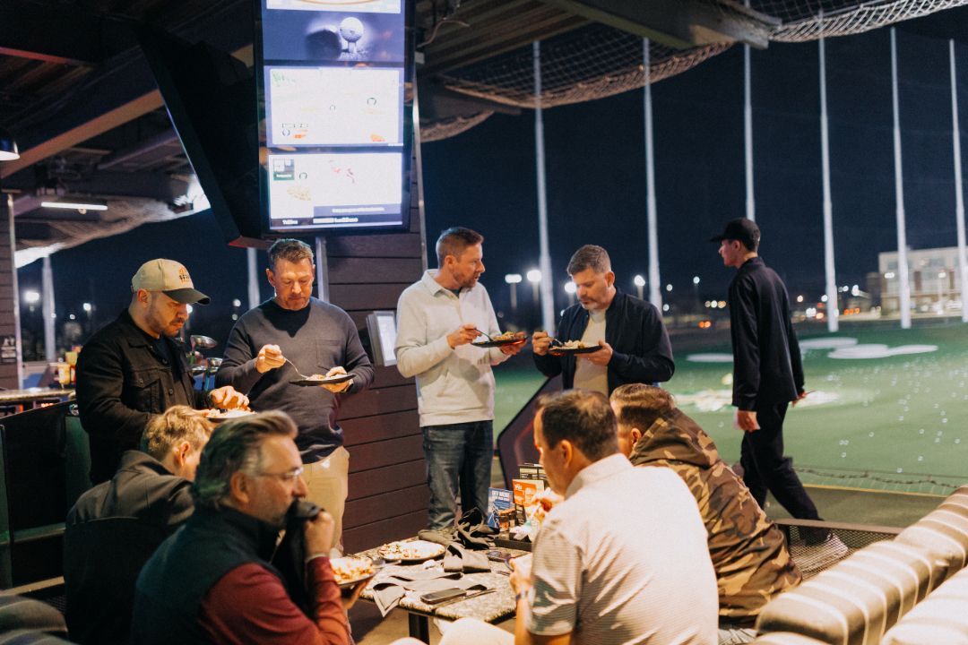 A group of men are sitting at a table eating food.