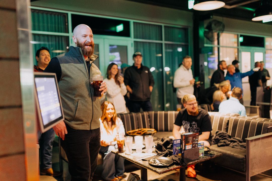 A man is standing in front of a group of people sitting on a couch.