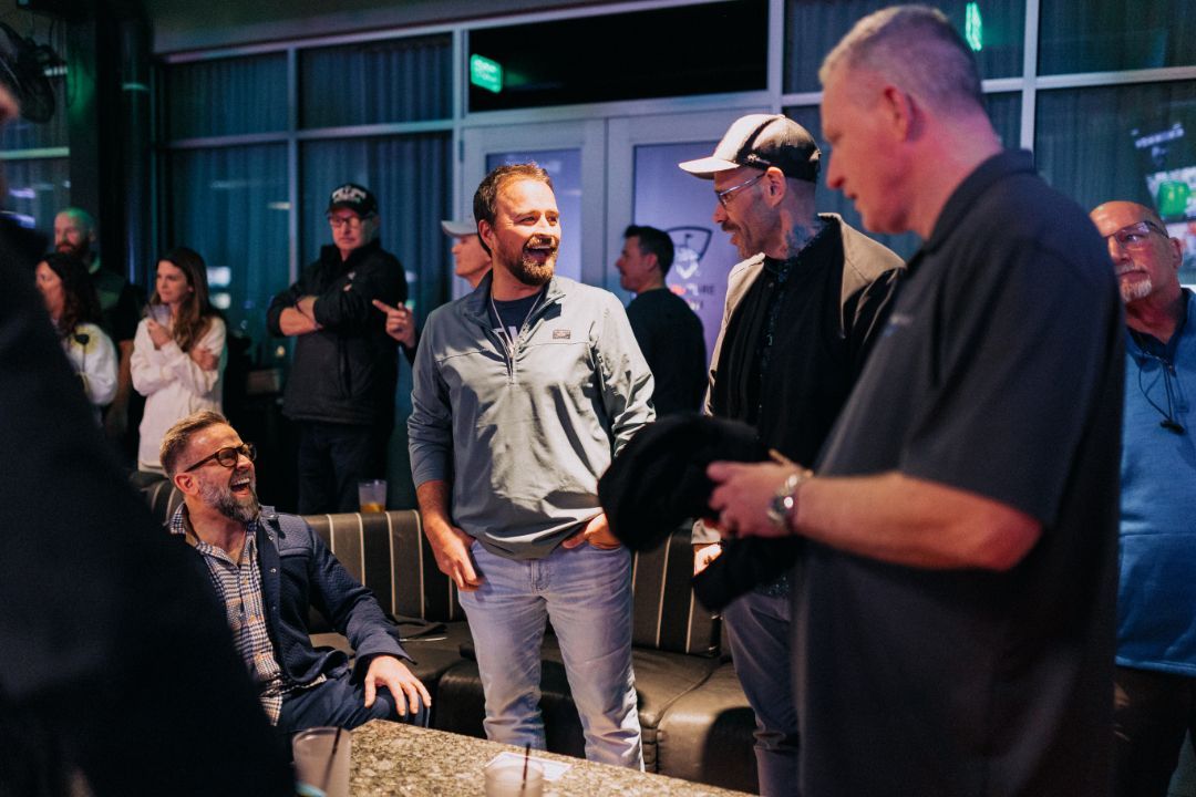 A group of men are standing around a table in a room.