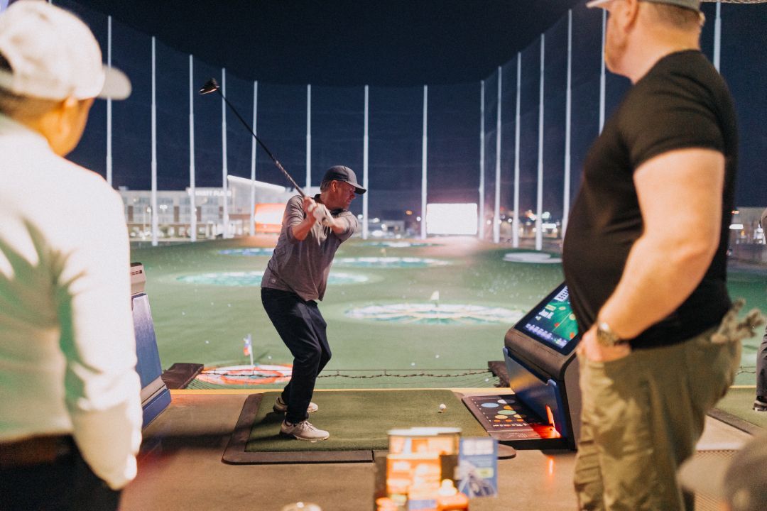 A man is swinging a golf club on a golf course while a woman watches.