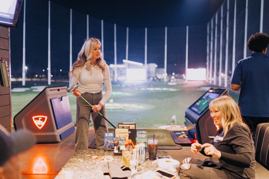 Two women are playing golf at a golf course at night.