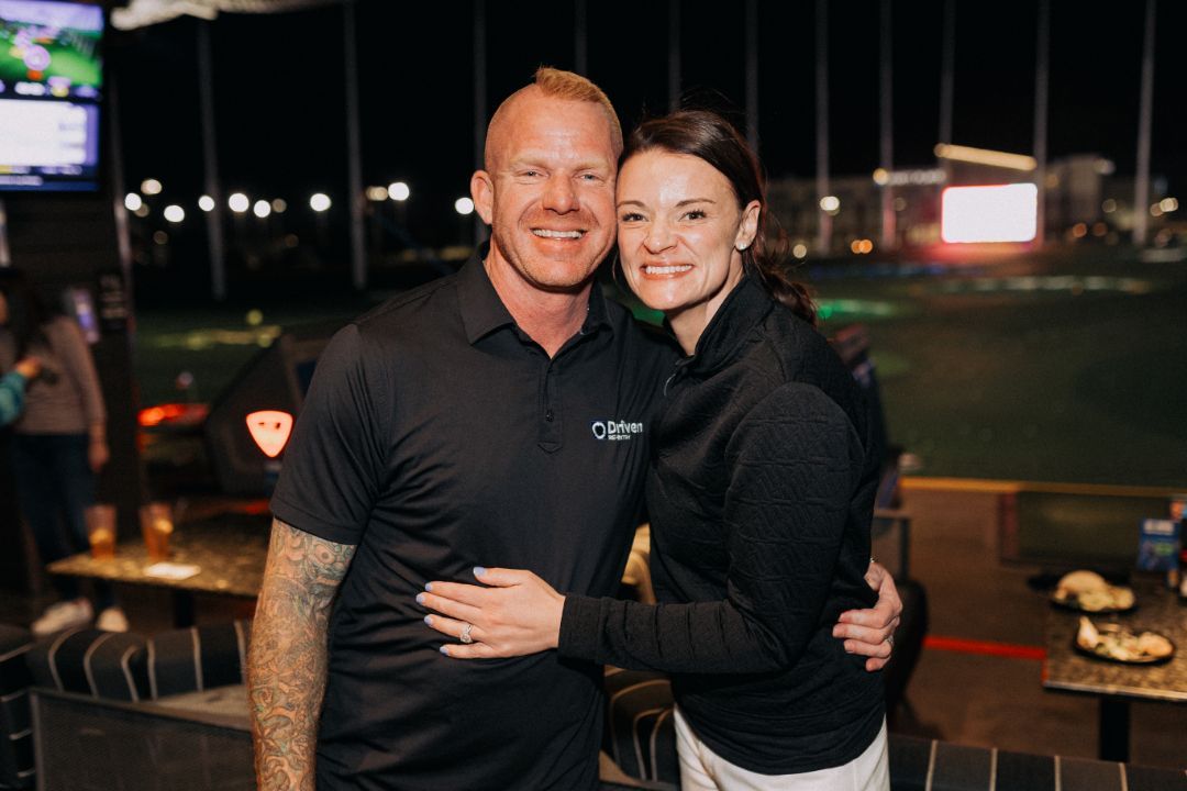 A man and a woman are posing for a picture at a golf course.