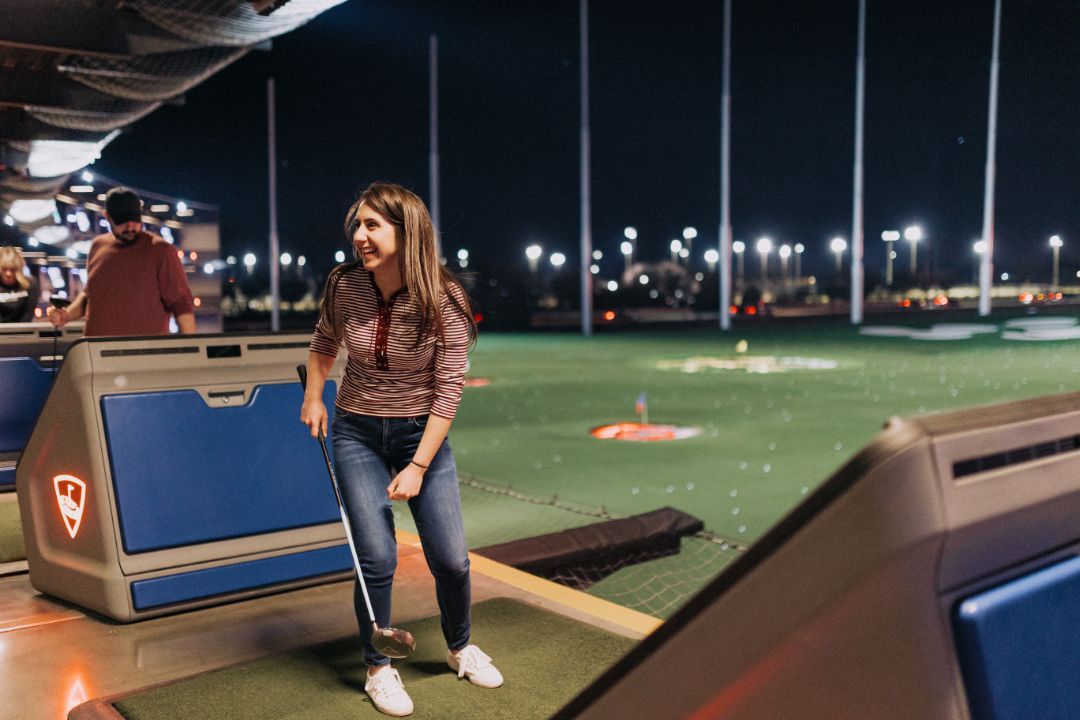 A woman is playing golf on a golf course at night.