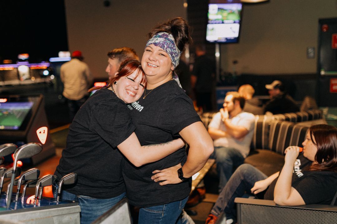 Two women are hugging each other in a bowling alley.