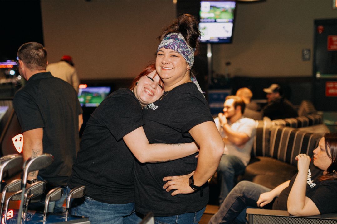 Two women are hugging each other in a bar.