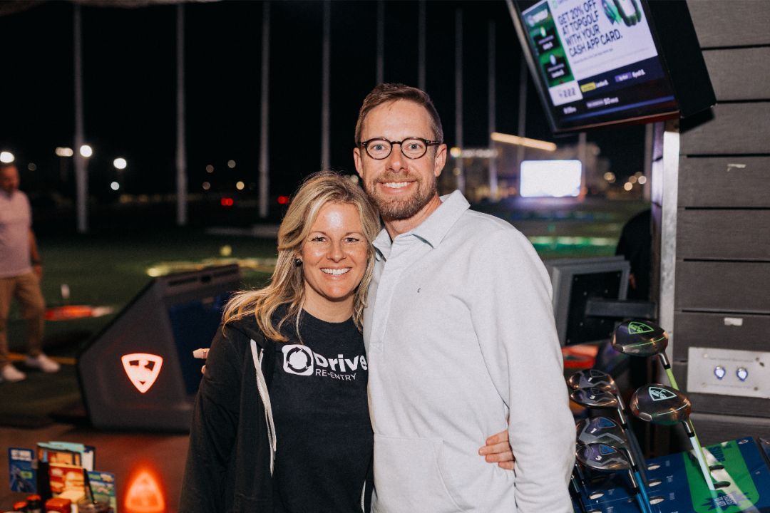 A man and a woman are posing for a picture at a golf course.