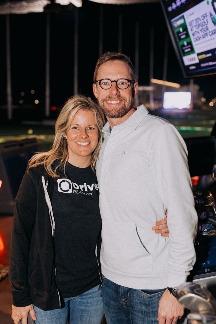 A man and a woman are posing for a picture in a bowling alley.