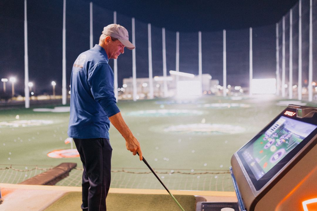 A man is playing golf on a golf course at night.