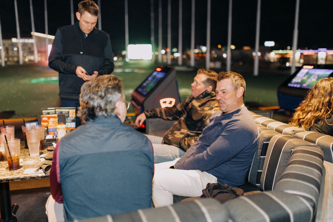 A group of people are sitting on a couch talking to each other.