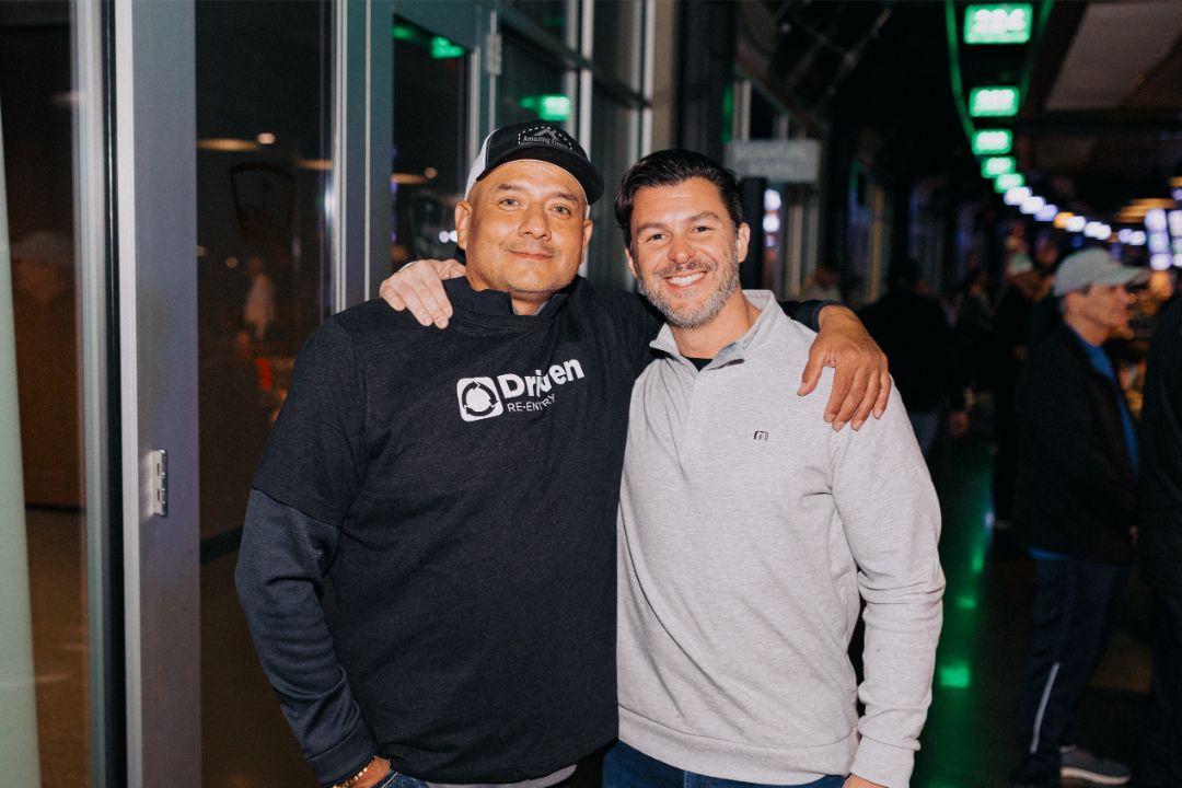 Two men are posing for a picture together in a dark room.