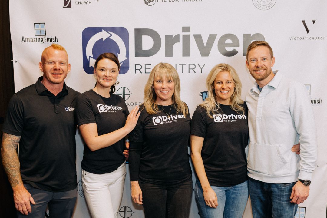 A group of people are posing for a picture in front of a sign that says driver registry.