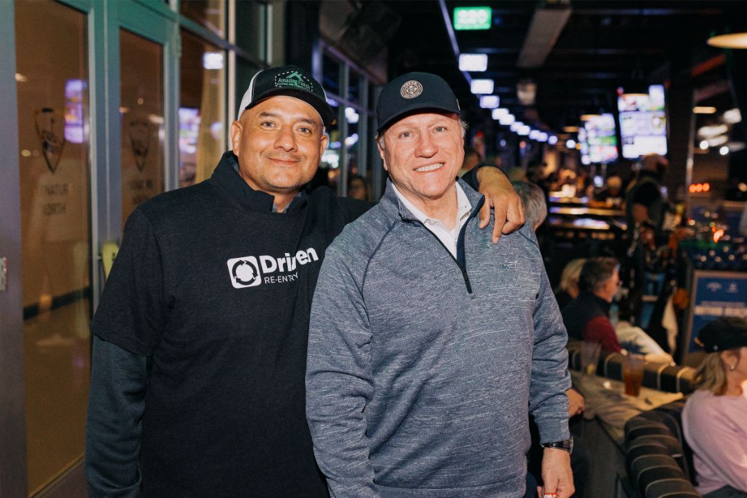 Two men are posing for a picture together in a restaurant.