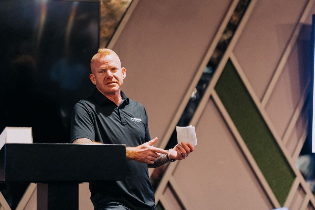 A man is standing at a podium holding a piece of paper.