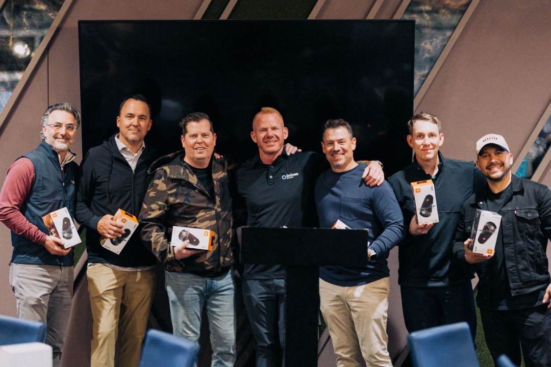 A group of men are posing for a picture in front of a television.