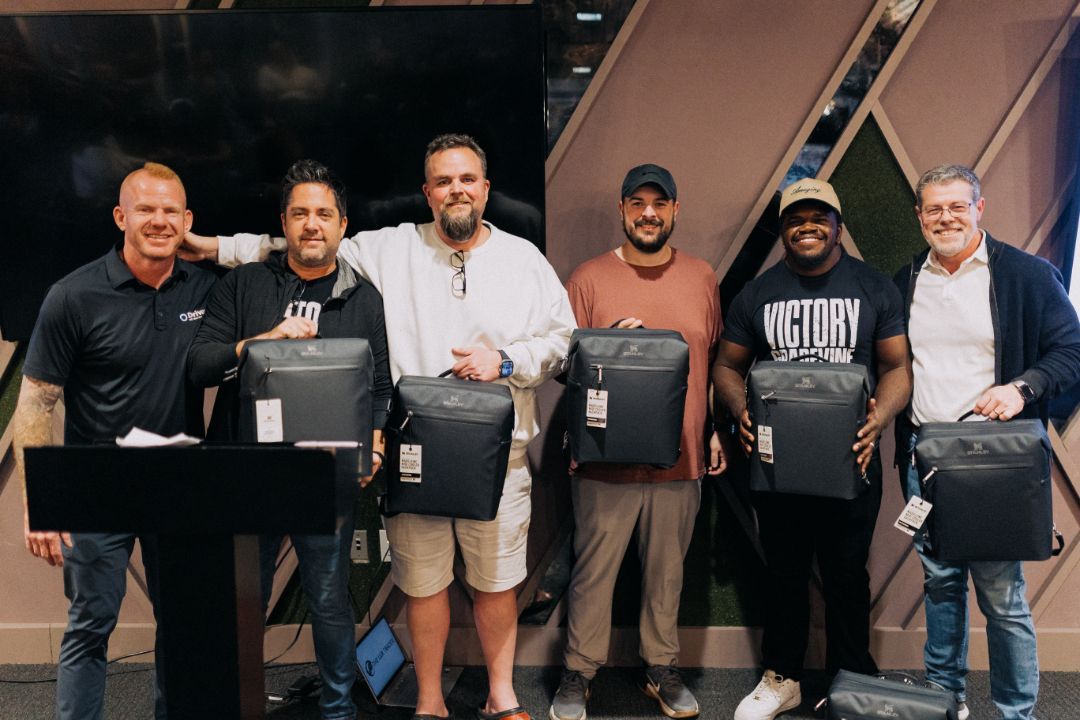 A group of men are standing next to each other holding bags.