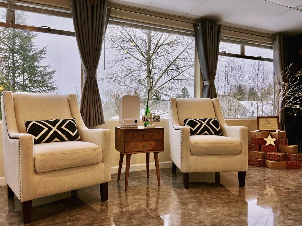 A living room with two chairs and a table in front of a window.