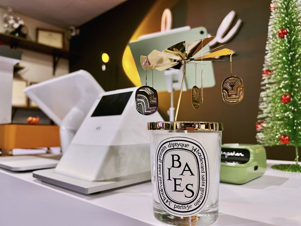 A candle is sitting on a shelf next to a christmas tree.