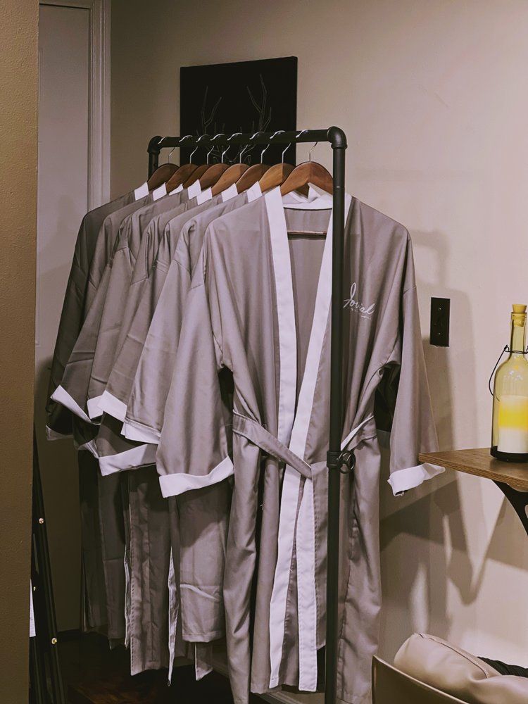 A row of robes are hanging on a rack in a room.