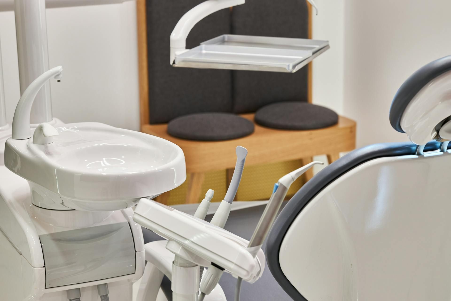 Modern dental office with a white dental chair, sink, and overhead exam light