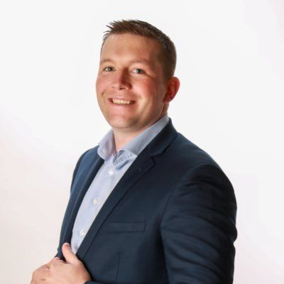 A man in a suit and white shirt is smiling for the camera.