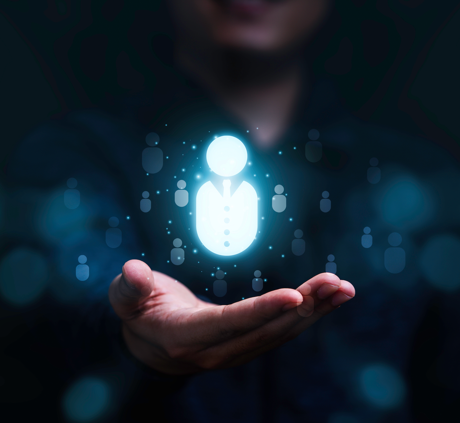 A person is holding a glowing icon of a person in their hand.