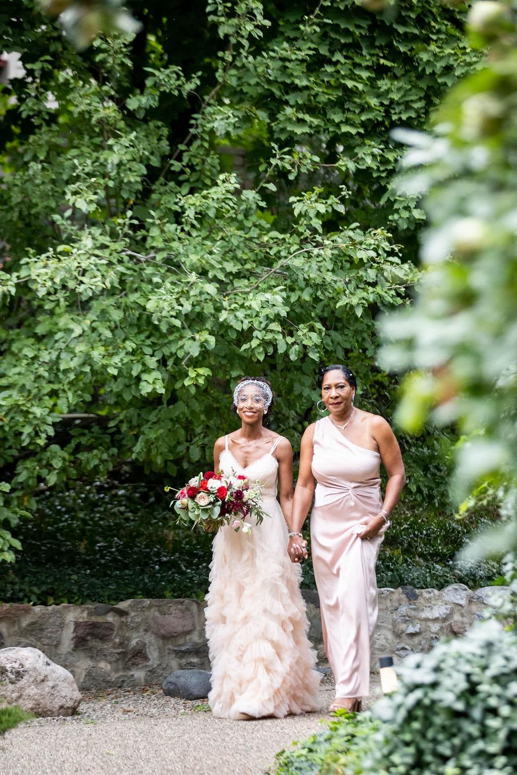 A bride and her mother are walking down the aisle at a wedding.