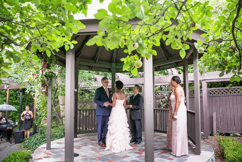 A bride and groom are getting married under a gazebo.