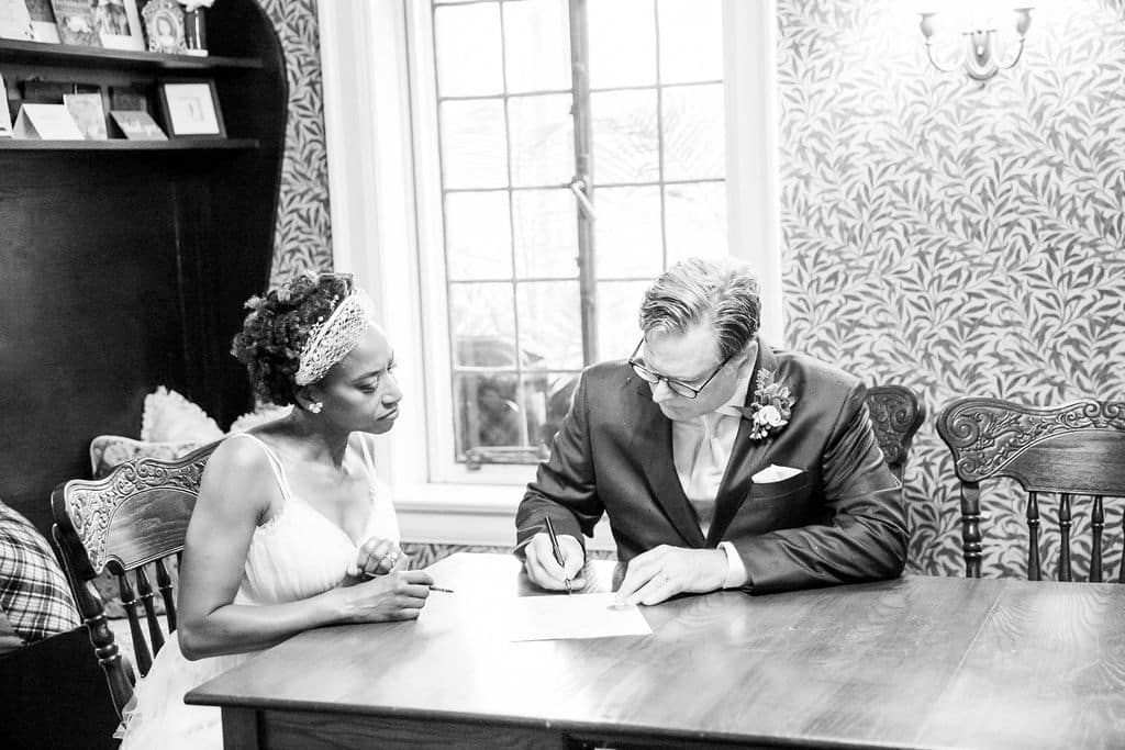 A bride and groom are signing a document at a table.