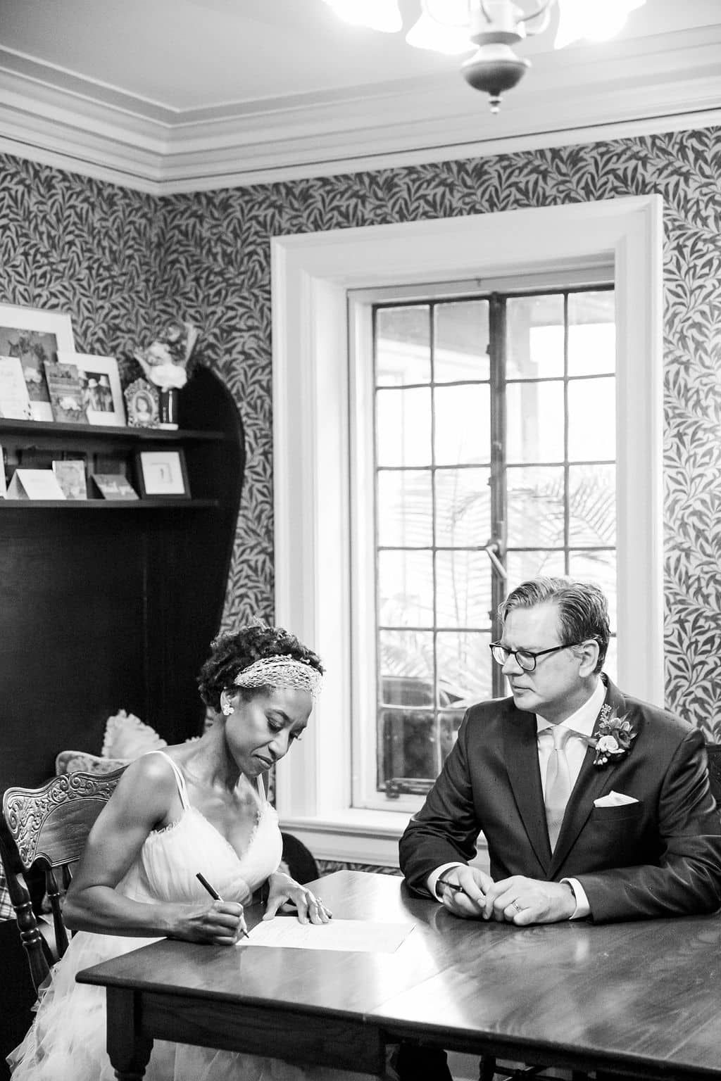 A bride and groom are sitting at a table signing a document.