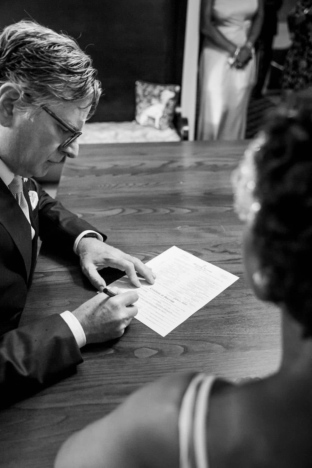 A black and white photo of a man and woman signing a document.