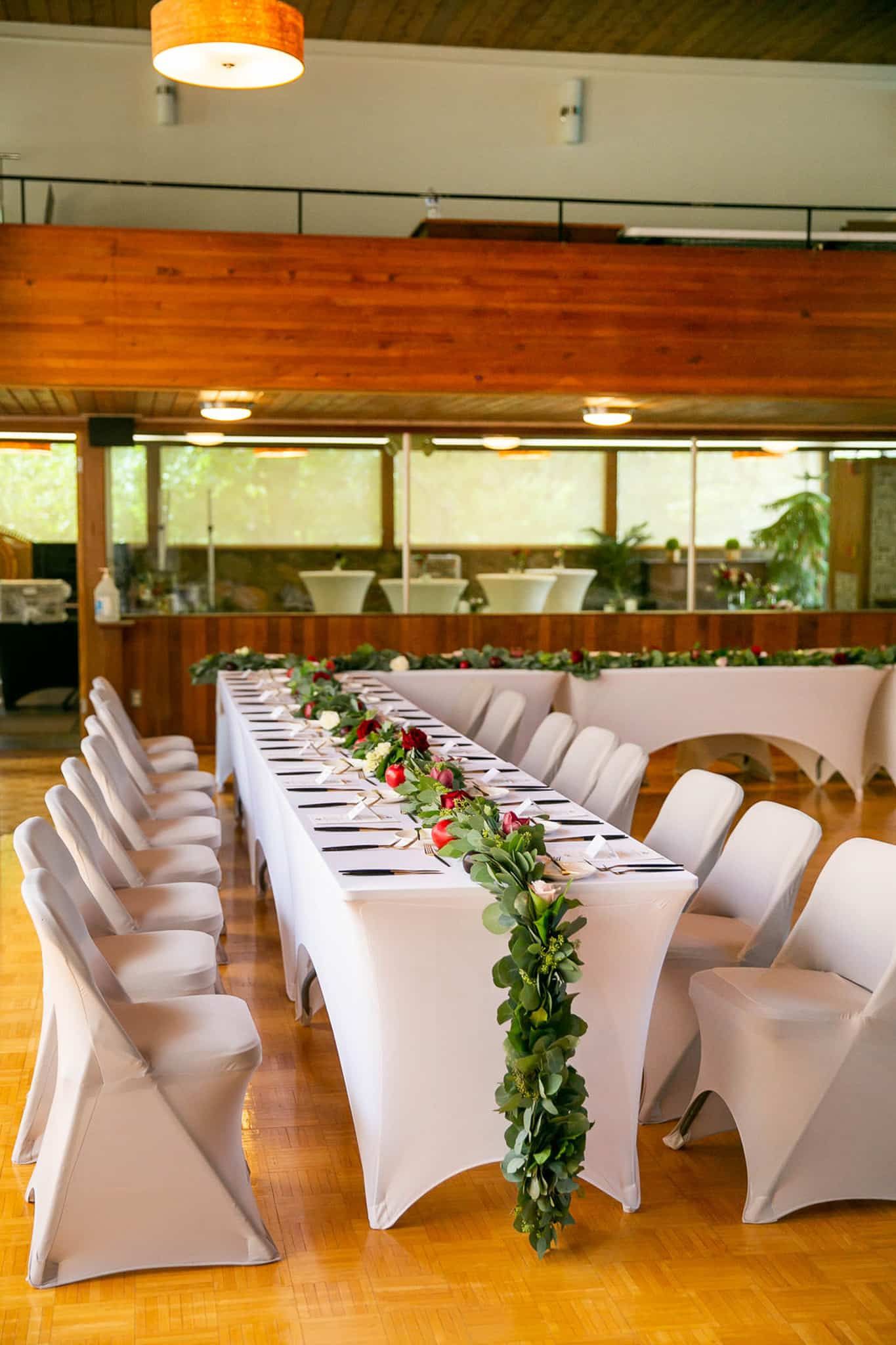 A long table and chairs are set up for a wedding reception.