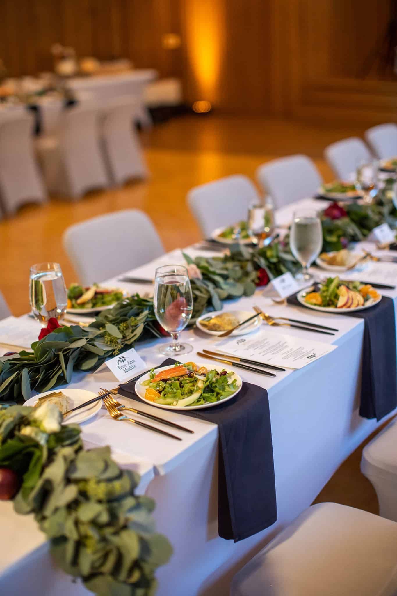 A long table with plates of food and wine glasses on it.