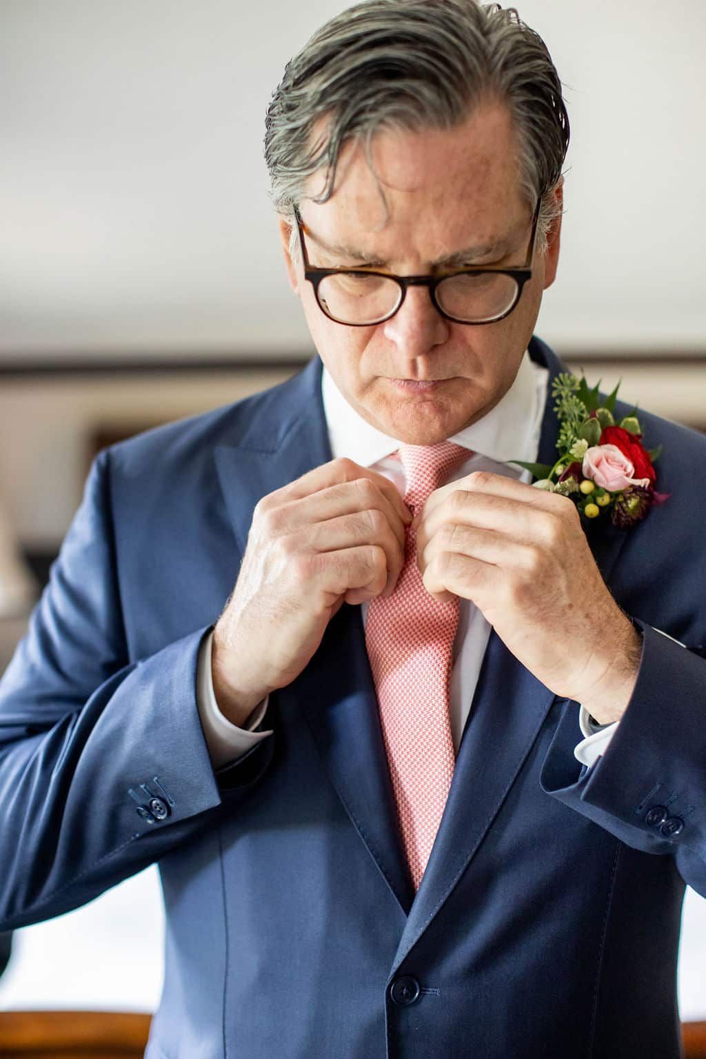 A man in a suit and tie is fixing his tie.