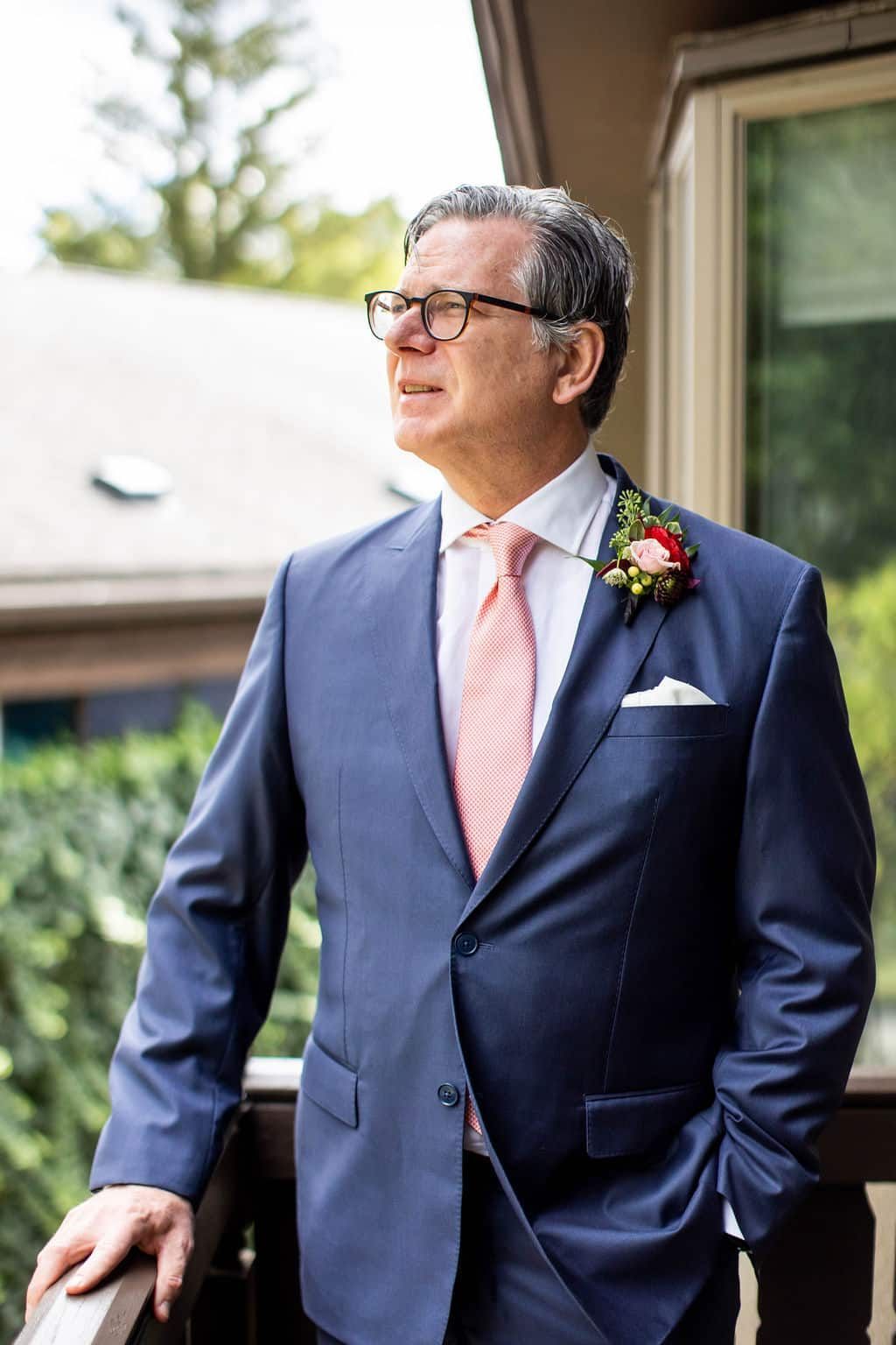 A man in a suit and tie is standing on a balcony.
