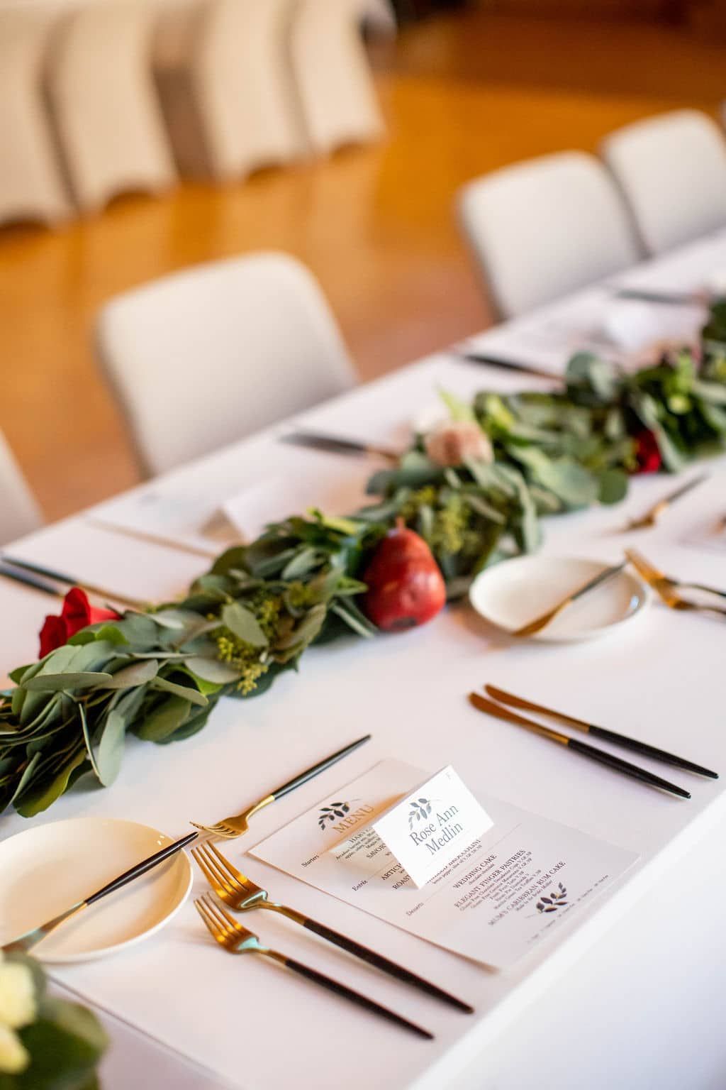 A long table with plates , silverware , and flowers on it.