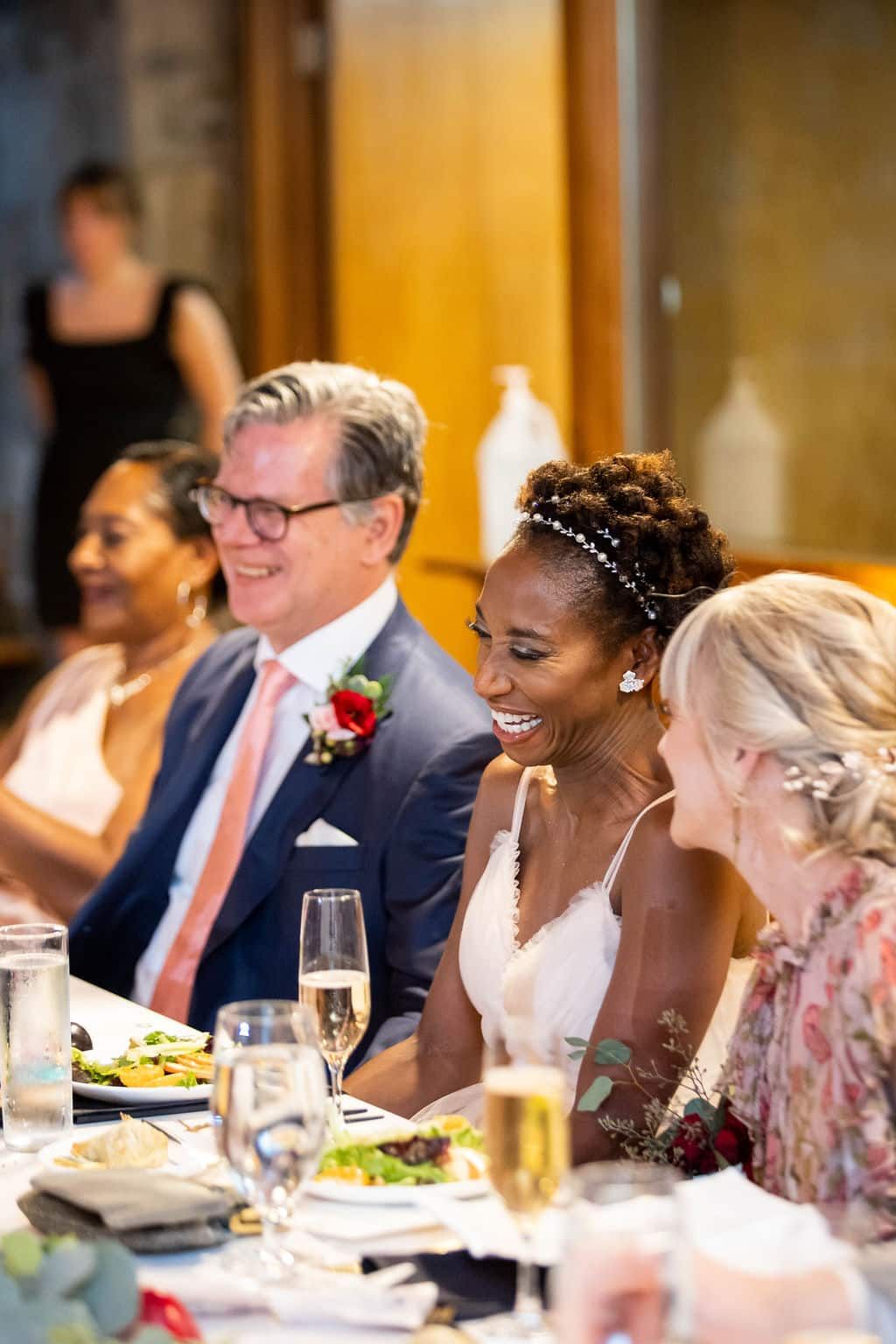 A bride and groom are sitting at a table at a wedding reception.