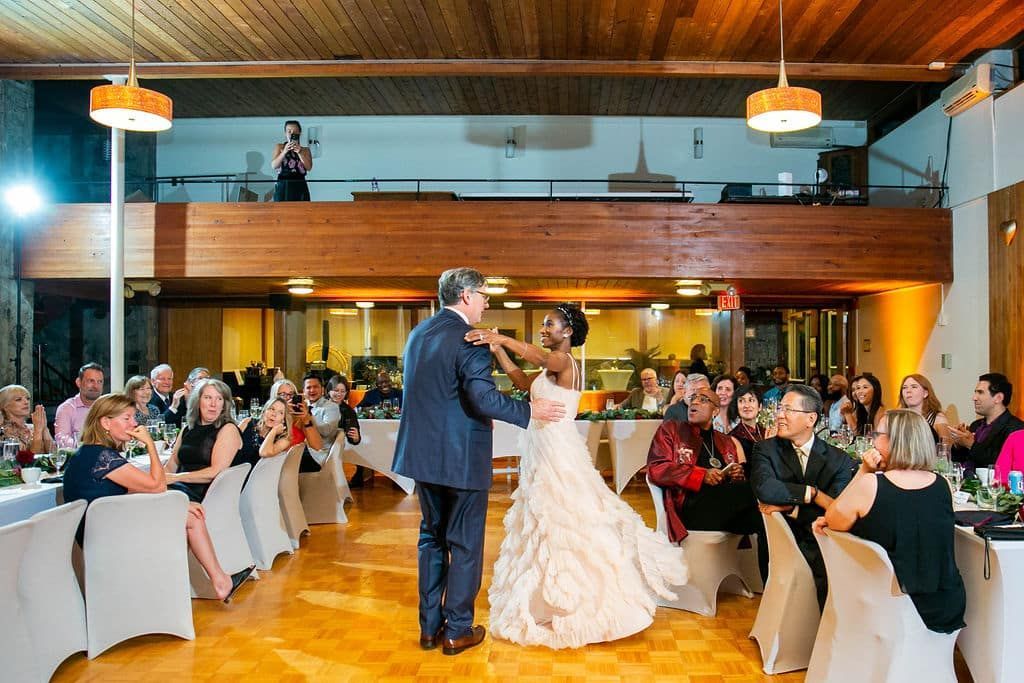 A bride and groom are dancing in front of a crowd at a wedding reception.