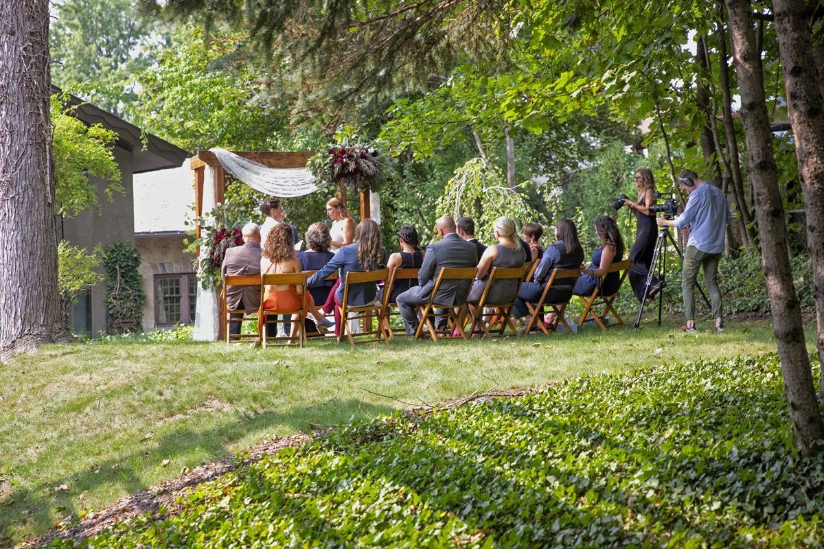 A group of people are sitting in chairs at a wedding ceremony in the woods.