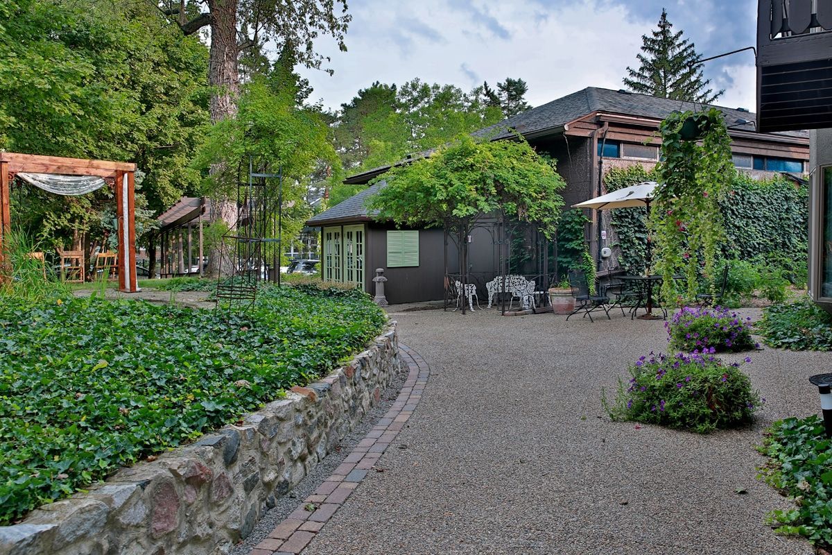 A gravel driveway leading to a house surrounded by trees and bushes.