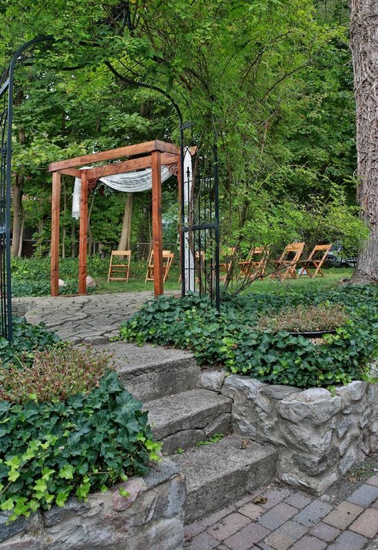 A stone staircase leading up to a wooden archway in a garden.