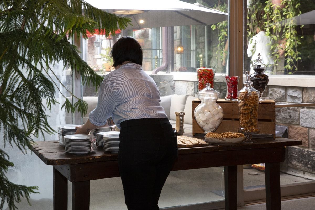 A woman is standing in front of a table filled with food.