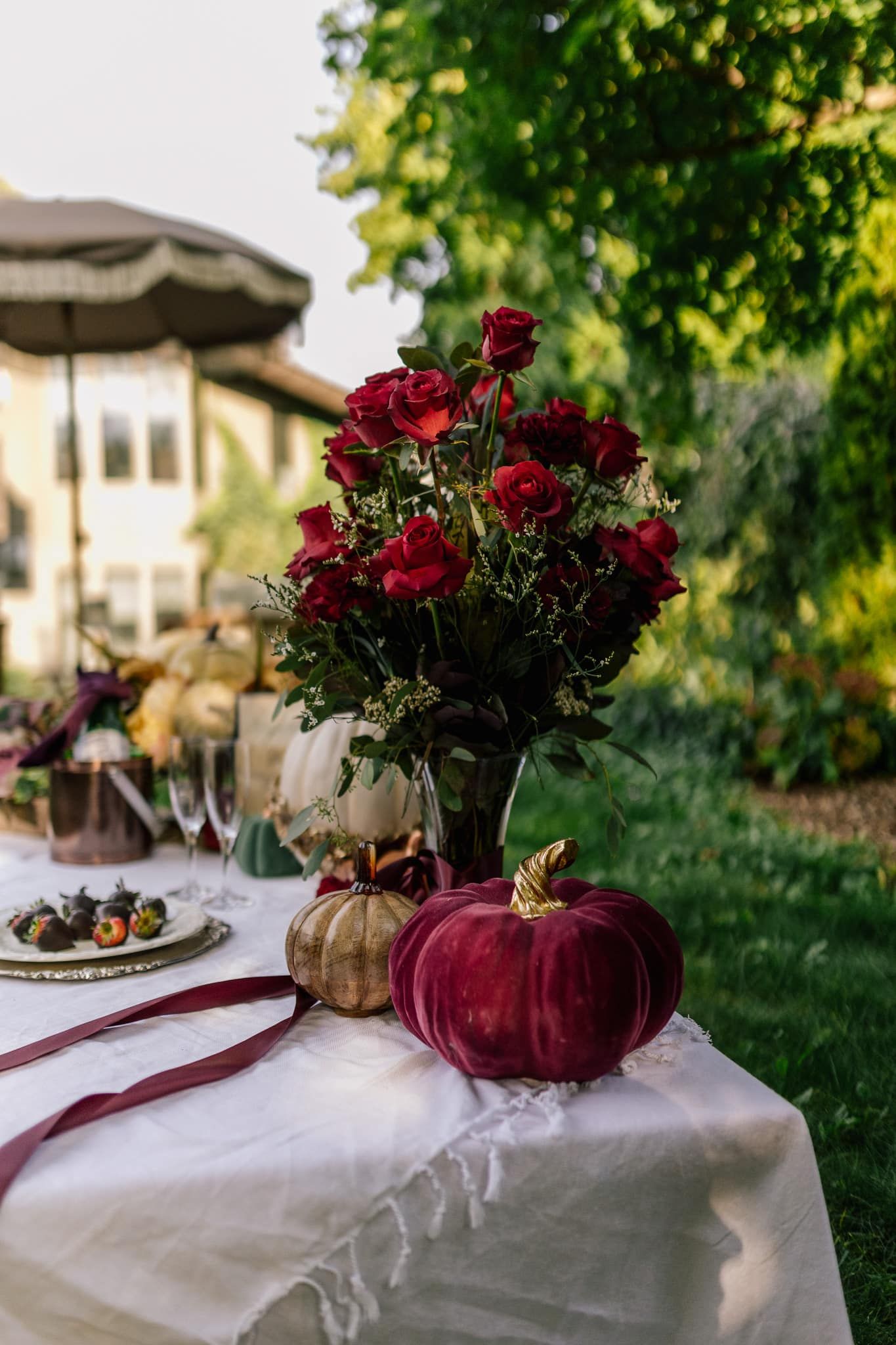 A table with a vase of flowers and pumpkins on it.