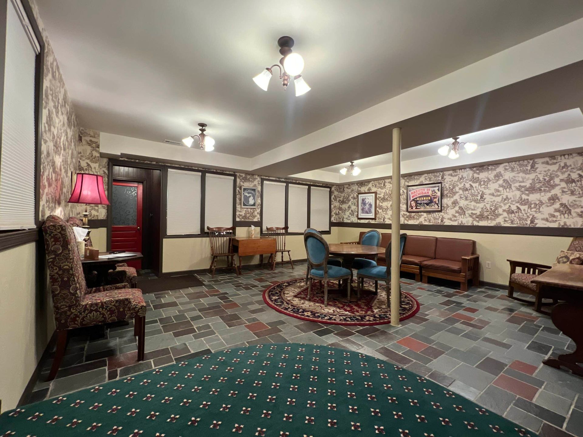 A living room with a couch , chairs , tables and a rug.