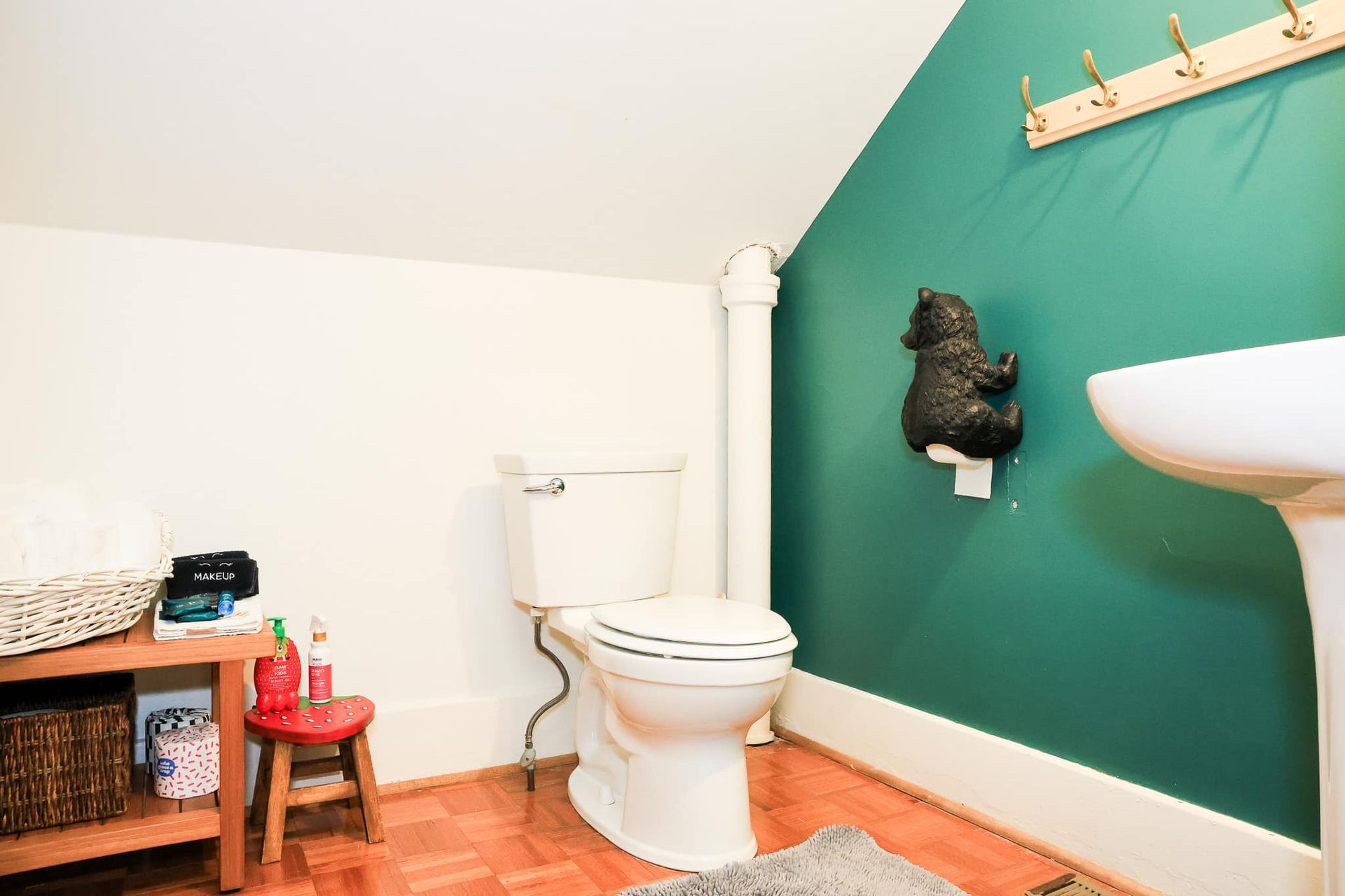 A bathroom with a toilet , sink , and green walls.