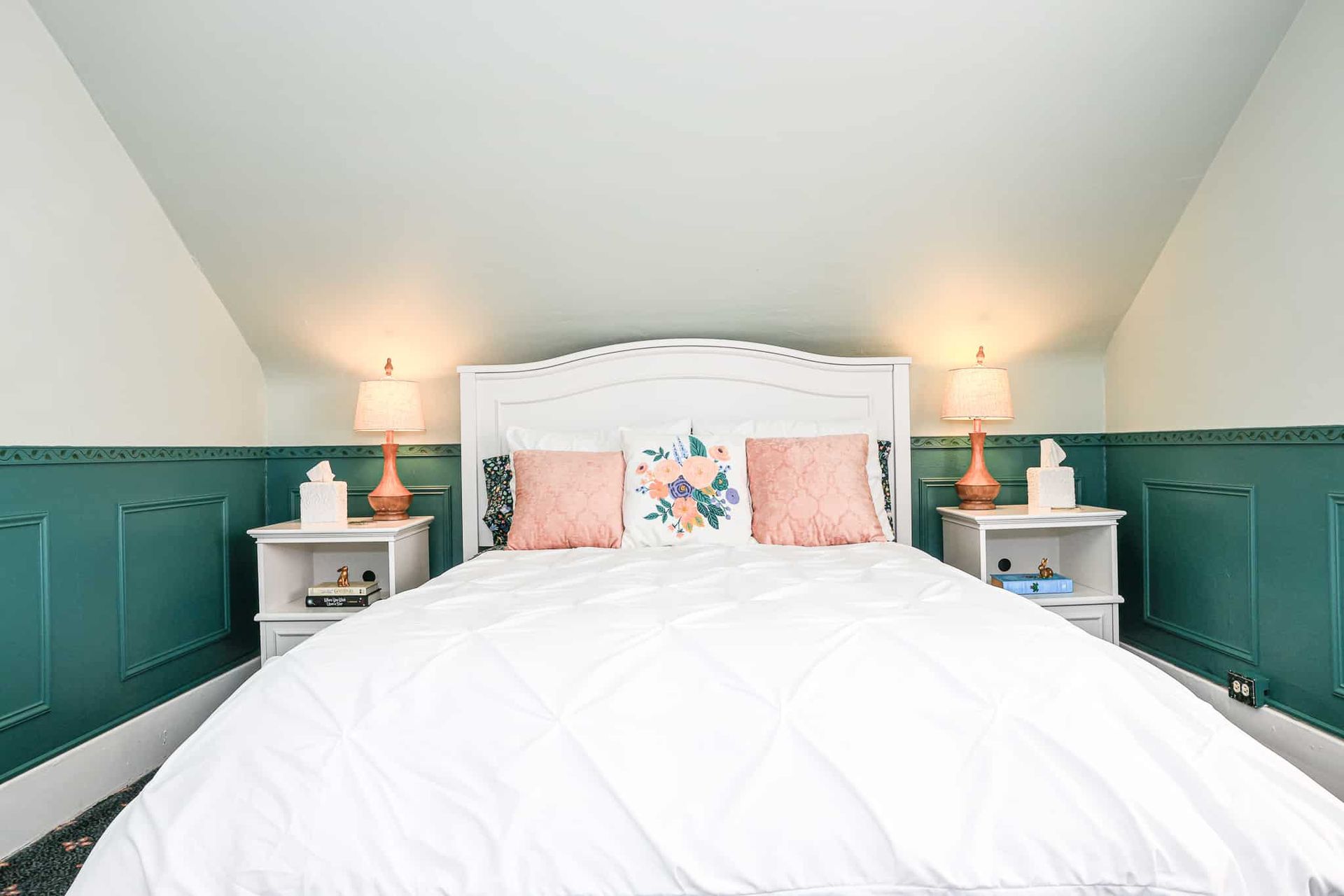 A bedroom with a bed , two nightstands and two lamps.