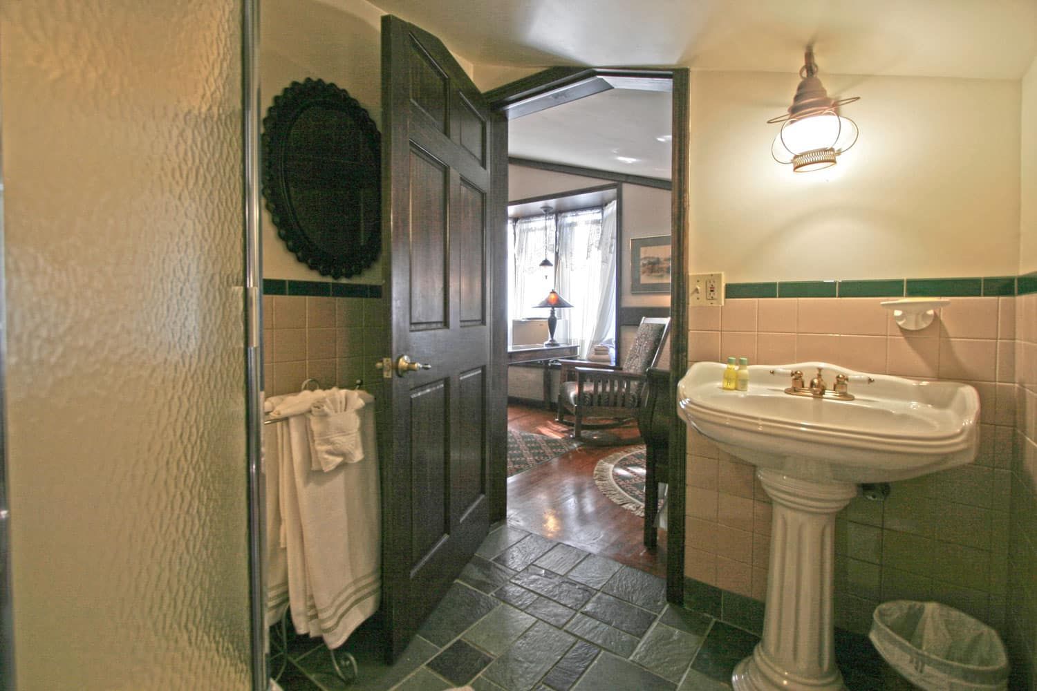 A bathroom with a pedestal sink and a walk in shower.