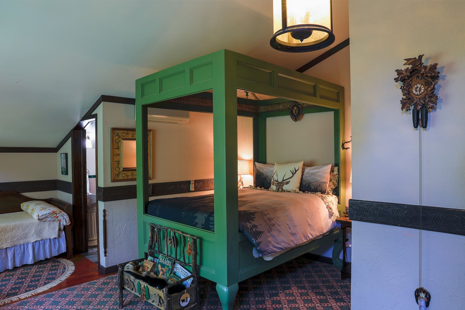 A bedroom with a green four poster bed and a cuckoo clock on the wall.